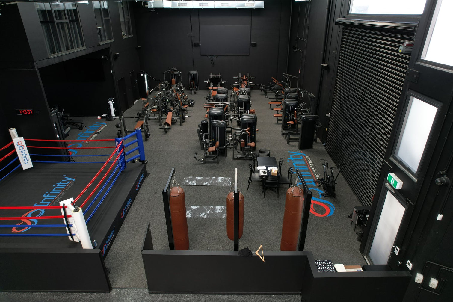 Large commercial gym floor with machines and a boxing ring